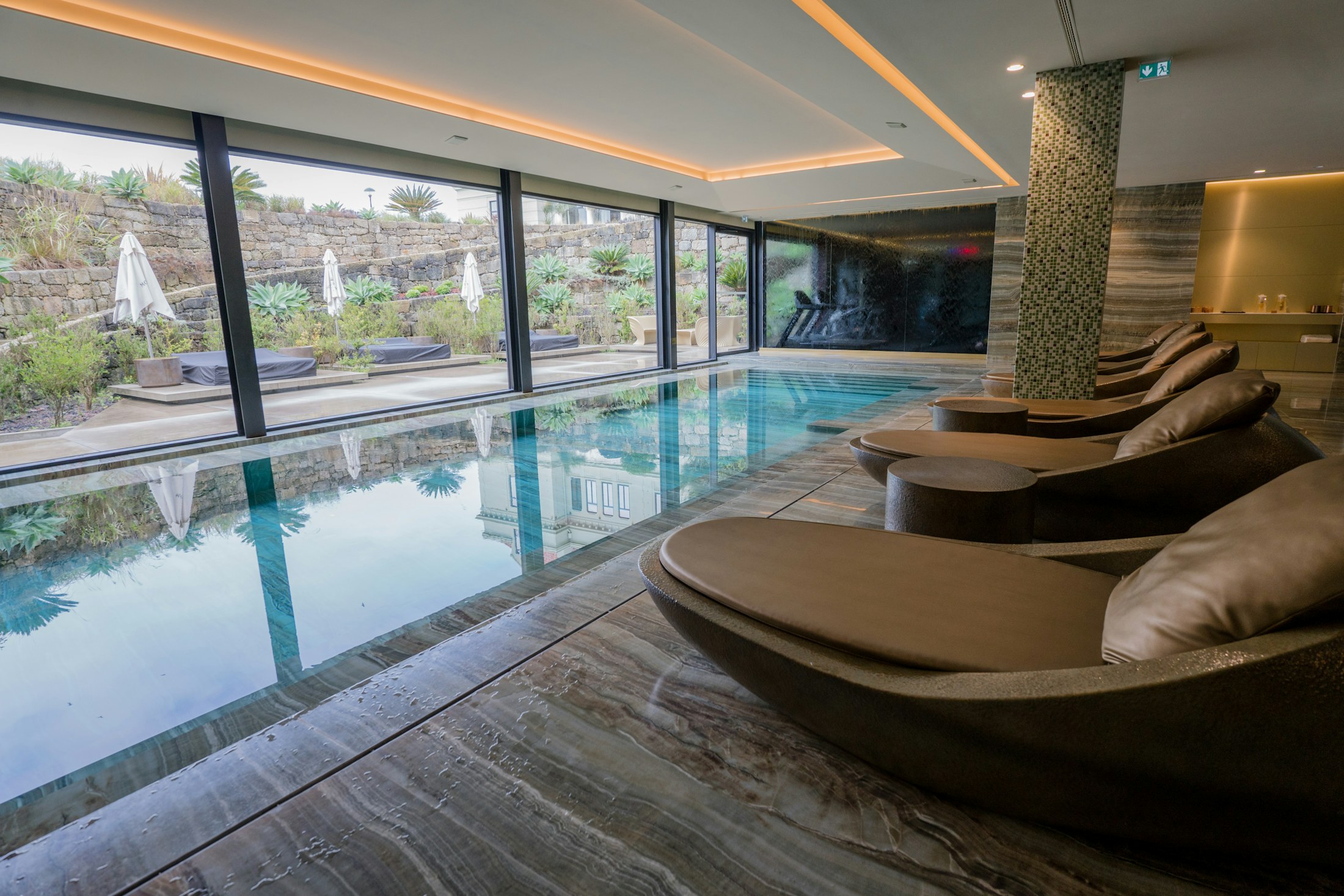 Indoor spa pool with lounge chairs and glass walls